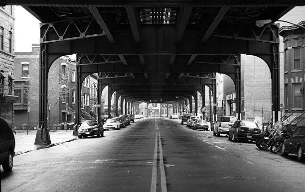 Under the train view down a street in Queens with train rail above queens new york city stock pictures, royalty-free photos & images