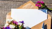 Static flowers and an envelope with an empty postcard. An empty postcard made of white paper and an envelope made of kraft paper, a letter with a place to copy the text, a greeting or an invitation.