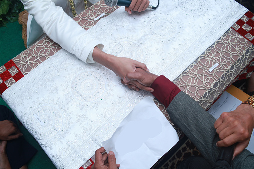 Muslim wedding ceremony. The marriage process for Indonesian Muslim bride-to-be is called Ijab Kabul in Akad Nikah. handshake between the groom and the bride's father.