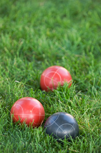 Black and red bocce balls nestled in lush green grass.