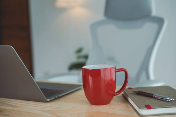 istock Close up view of red cup of coffee in worktable workpalce with laptop, chart documents, notebook, and decoration in home office room. Work at home place in the living room concept. 1727187579