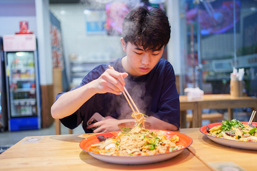 Asian man eating in can guan