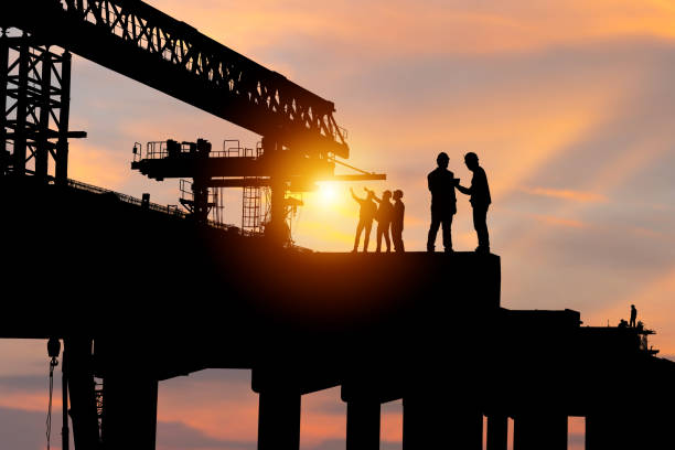 istock Silhouette of Engineer and worker checking project at building site background, construction site at sunset in evening time 1727192840