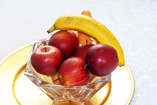 Slose-up studio shoot of bananas and apples in a glass container