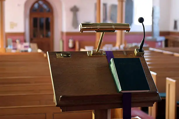"A modern wooden church pulpit with microphone, brass lamp and closed bible.This file has been updated and replaced after its original upload as there was a problem with a square around the microphone which has now been resolved.A similar new image from the same location is now also available in a larger size:"