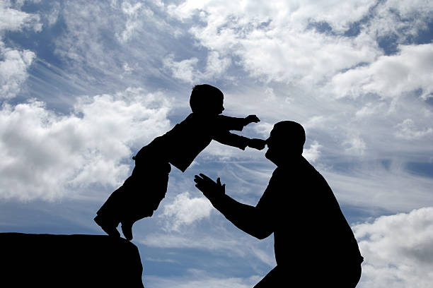 Father and Son II Son jumping into the arms of his father, silhouetted to create dramatic effect leap of faith stock pictures, royalty-free photos & images