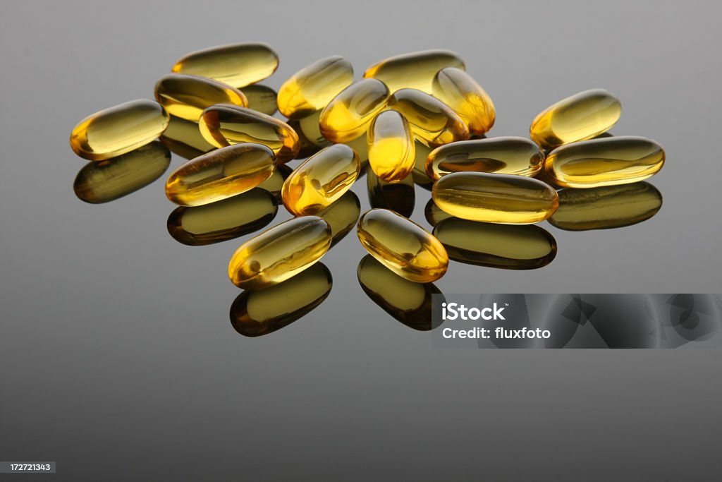 Fish Oil Capsules Fish oil capsules, a source of omega-3 fatty acids, on a gradient gray reflective back ground. Acid Stock Photo