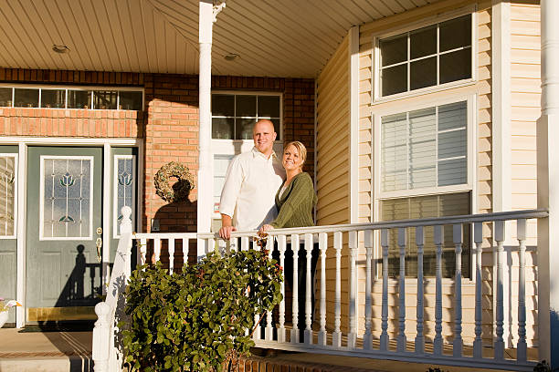 Married Couple at Home Photo of a young married couple standing on the porch in front of their home. mormon woman photos stock pictures, royalty-free photos & images