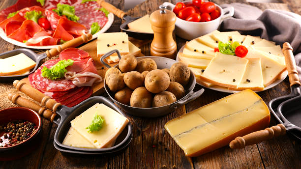 Queso raclette con ingrediente en la mesa: comida tradicional francesa en invierno - foto de stock