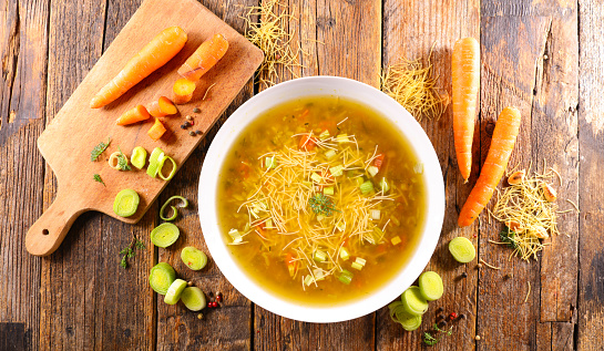 Homemade green peas with carrot and chicken meat in a pan, close up on a blue wooden table top