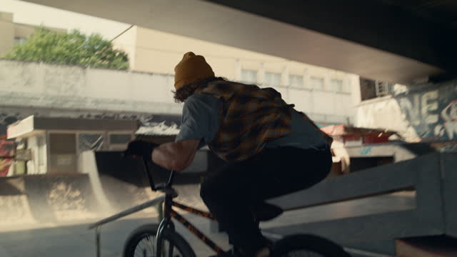Energetic boy performing tricks on bmx bicycle in public skate park.
