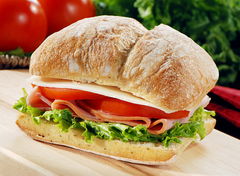 Sliced ham sandwich with lettuce,tomato and cheese on a focaccia bread. More sandwichs...