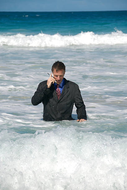 hombre de negocios hablando por teléfono móvil desde el mar - stranded men telephone beach fotografías e imágenes de stock