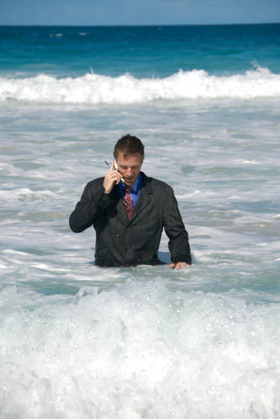 uomo d'affari parlando sul cellulare dal mare - stranded beached beach businessman foto e immagini stock