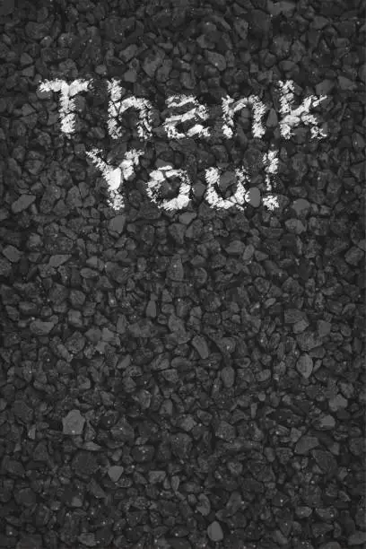 Vector illustration of Black or dark grey coloured pebbles gravel road v vector vertical backgrounds with small stones pattern allover like a pebbled road with gratitude text Thank You painted in white color paint