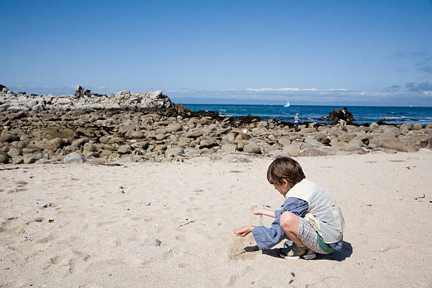 Boy Playing on the beach Child playing in the sand at the ocean's edge. mm1 stock pictures, royalty-free photos & images