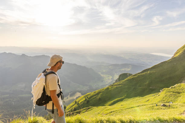 istock Man hikes along grassy mountain ridge at sunrise 1727278233