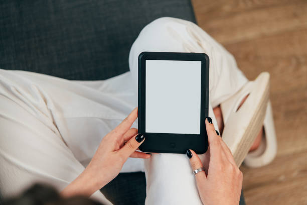 istock Young woman sitting the couch with an e-book 1727278753