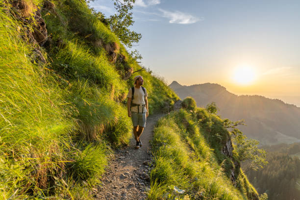 istock Man hikes along grassy mountain ridge at sunrise 1727281898