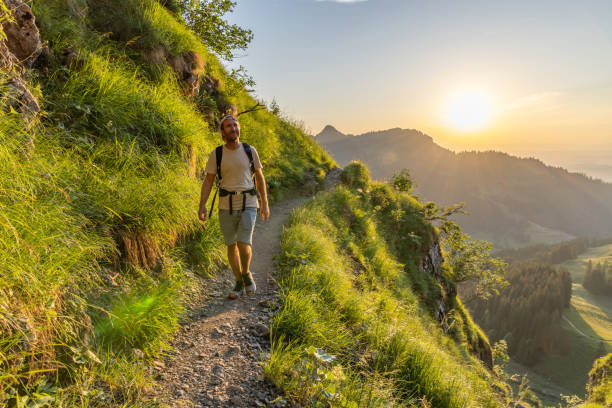 istock Man hikes along grassy mountain ridge at sunrise 1727281899