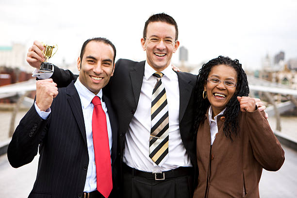 un grupo de profesionales mirando y sonriendo trofeo de retención - cheering business three people teamwork fotografías e imágenes de stock
