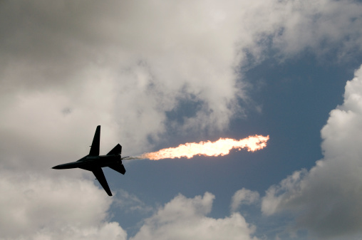 A military jet burns off fuel while screaming overhead.