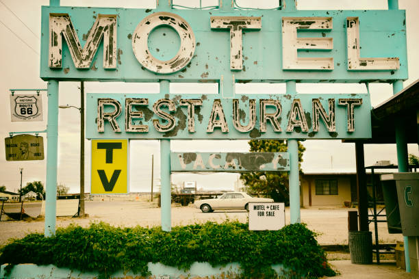 A vintage motel sign in front of a large, modern hotel
