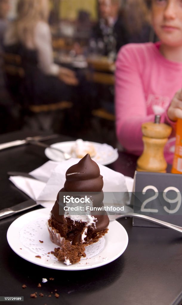 Ragazza nel caffè all'aperto di mangiare Marshmallow al cioccolato dolce Cupcake - Foto stock royalty-free di Alimentazione non salutare