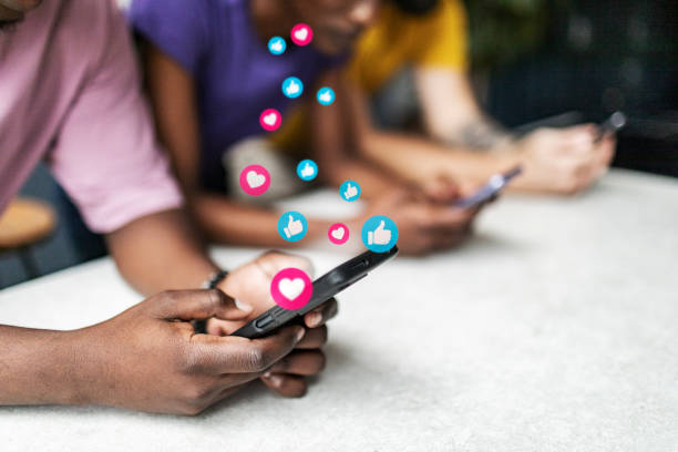 Closeup of hands using mobiles Closeup of hands using mobiles with digital generated social media icons - heart, thumbs up heart emoji phone stock pictures, royalty-free photos & images