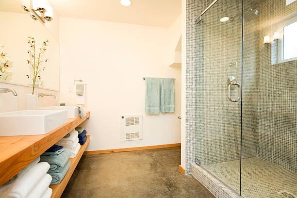 A simple, tiled shower stall in a public washroom, equipped with a chrome shower fixture. A metal grab bar provides support, highlighting the functional and accessible design of the shared facility.