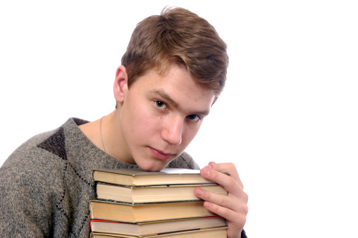 Portrait of a male student sitting reading a book preparing for exam isolated on white