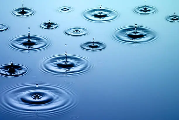 Photo of Close-up of falling raindrops and associated ripples