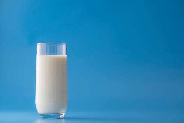 istock Glass of white milk isolated on blue background 1727323875