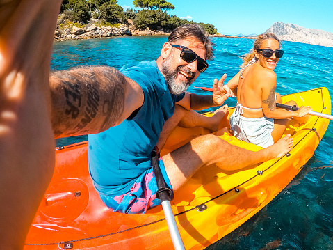 Happy couple of tourist taking selfie inside a kayak canoe in summer holiday travel vacation smiling and having fun at the camera. Cheerful man and woman on a boat. Blue clean beautiful sea ocean