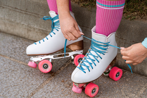 Close-up detail of a skater's hands tying the laces of a pair of quad roller skates.