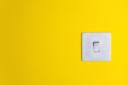 Close up of a light switch on a yellow wall.