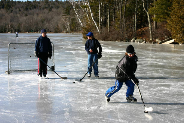 TRAKAI, LITHUANIA - JANUARY 7, 2016: Children playing ice hockey in the rink in winter Trakai. Ice hockey is a contact team sport played on ice, usually in a rink.