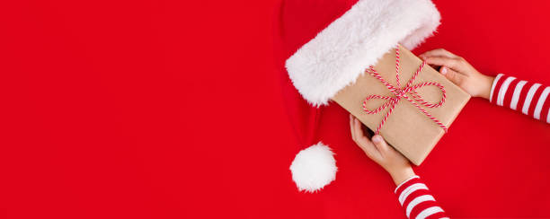 istock gift box in children's hands on a red background, presenting a gift, christmas background 1727339854