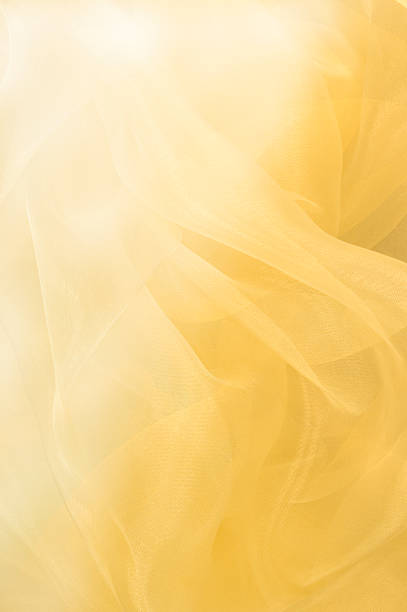 Flowing Yellow Abstract Background Yellow ethereal fabric flows with light and shadows. mustard yellow fabric stock pictures, royalty-free photos & images