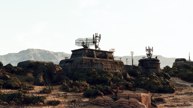A desert landscape with rocks and trees surrounding a military base war bunker