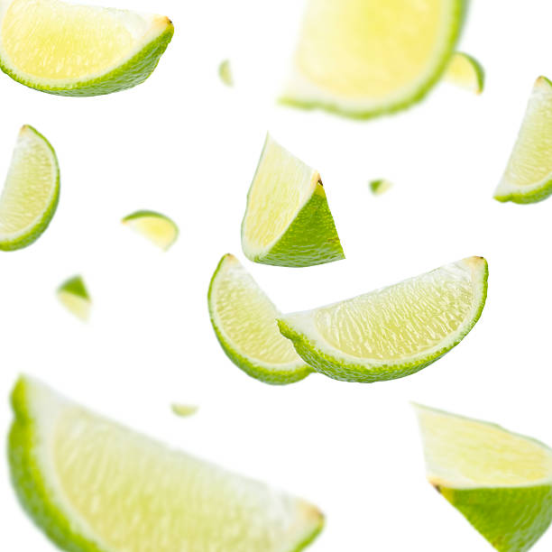 Slices of lime everywhere on white background stock photo