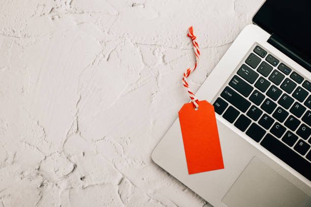 istock Business gift idea in the digital era - A wrapped present with a red tag on a laptop keyboard. E-commerce and Black Friday event. 1727358131