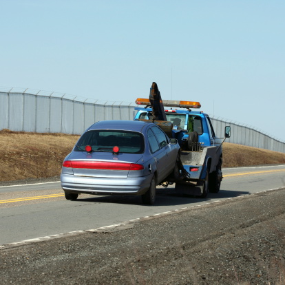 Tow truck towing a broken down vehicle on a secondary highway.
