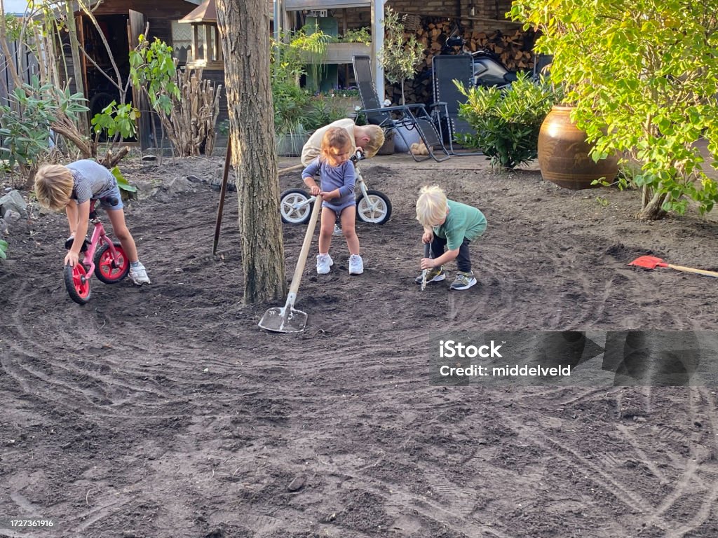 Grandchildren working in garden Grandchildren helping prepare the garden for new Grass 12-23 Months Stock Photo