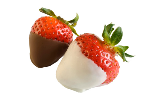 Two strawberries, one dipped in white chololate, the other dipped in milk chocolate, fresh, juicy and ready to eat!