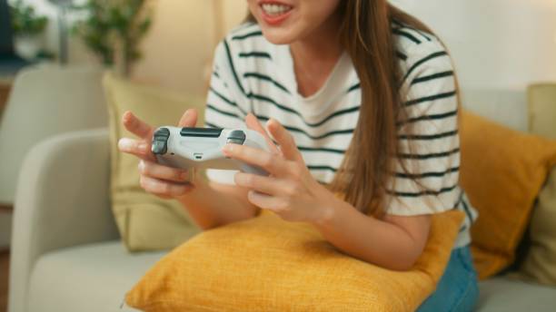 istock Attractive young Asian woman playing game using wireless joystick controller 1727375817