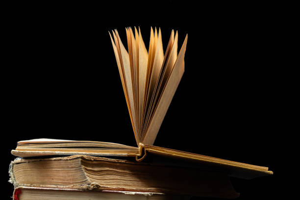 istock stack of old books with opened one on top on dark background. Old books in the library. Bookshelf shop. Knowledge publications, literature. Bookish bookstore, bookstore 1727376443