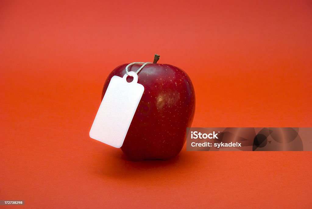 Apple on Red An apple on a red background with a blank price tag hanging off of it. Apple - Fruit Stock Photo
