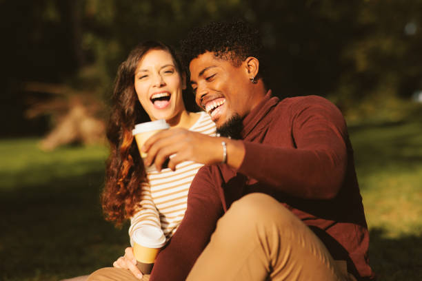 Jeune couple profitant d’un parc par une journée ensoleillée et buvant un café - Photo