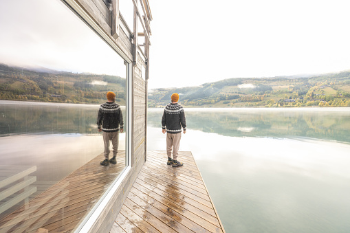 Young man relaxing outside of a floating sauna, he enjoys the freshness of the outdoors